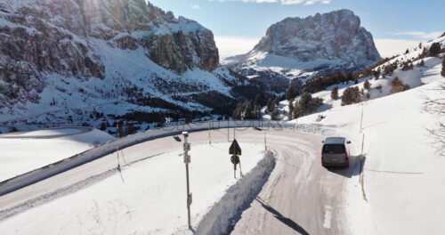 South Tyrol, Italy – January 12, 2025: Aerial drone view of a car moving through the Gardena Pass high mountain pass in the Dolomites - Starpik Stock