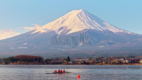 Aerial drone view of a rowing team of four people with a coxswain seated at the front practicing on Lake Kawaguchiko, with Mount Fuji on the background - Starpik Stock