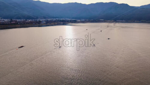 Aerial drone view of rowing boats moving on Lake Kawaguchiko near the Fujikawaguchiko town, Japan - Starpik Stock
