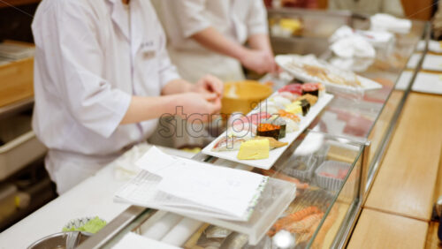 Close up of a chef preparing nigiri on a white plate at the Tsukiji Fish Market in Japan - Starpik Stock