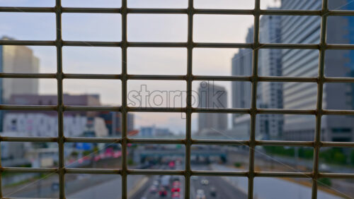 Close up of a fence with a blurred view of cars moving on the roads of Daiba, Japan in daylight - Starpik Stock