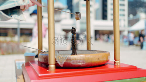 Close up of a purification water fountain at the Tsukiji Hongan-ji Temple with people walking on the blurred background - Starpik Stock