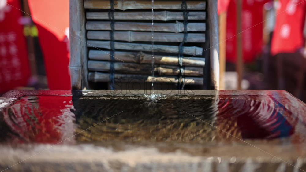 Close up of a small water fountain surrounded by red flags at the Senso-ji temple in Asakusa, Tokyo, Japan - Starpik Stock