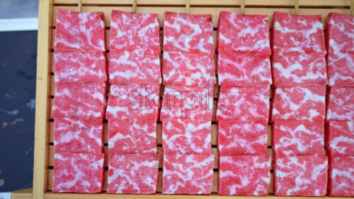Close up of multiple pieces of Wagyu beef on a wooden tray at a street food market in Japan - Starpik Stock