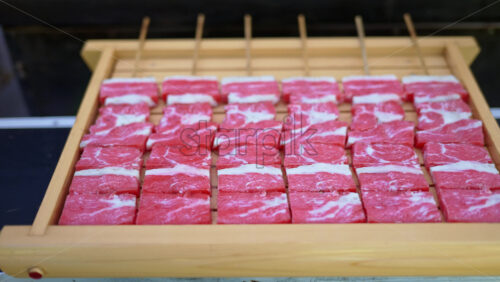 Close up of multiple pieces of Wagyu beef on a wooden tray at a street food market in Japan - Starpik Stock