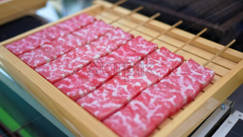 Close up of multiple pieces of Wagyu beef on a wooden tray at a street food market in Japan - Starpik Stock
