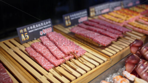 Close up of multiple pieces of Wagyu beef on a wooden tray at the Tsukiji Fish Market in Tokyo, Japan - Starpik Stock