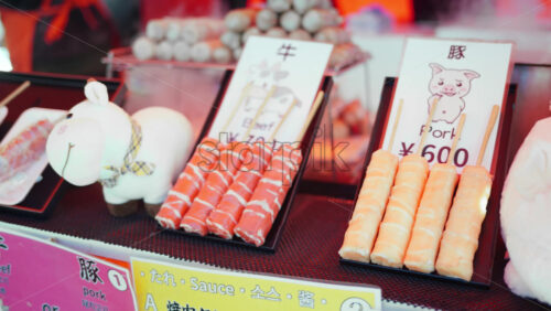Close up of pork and beef skewers at a street food market in Japan - Starpik Stock