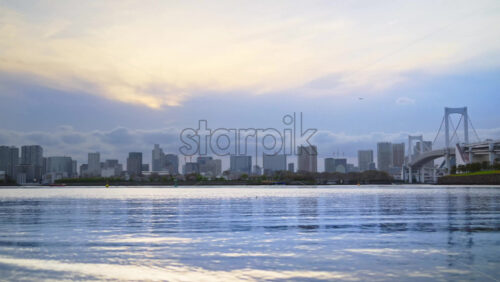 Distant view of the Rainbow Bridge and the skyline of Tokyo, Japan on a cloudy day - Starpik Stock
