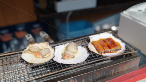 Grilled scallops and ell served on shells at the Tsukiji Fish Market in Japan - Starpik Stock