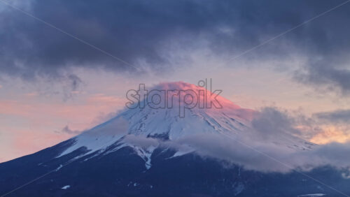 Video Aerial drone view of Mount Fuji with snow at the top and clouds moving around at sunset - Starpik Stock