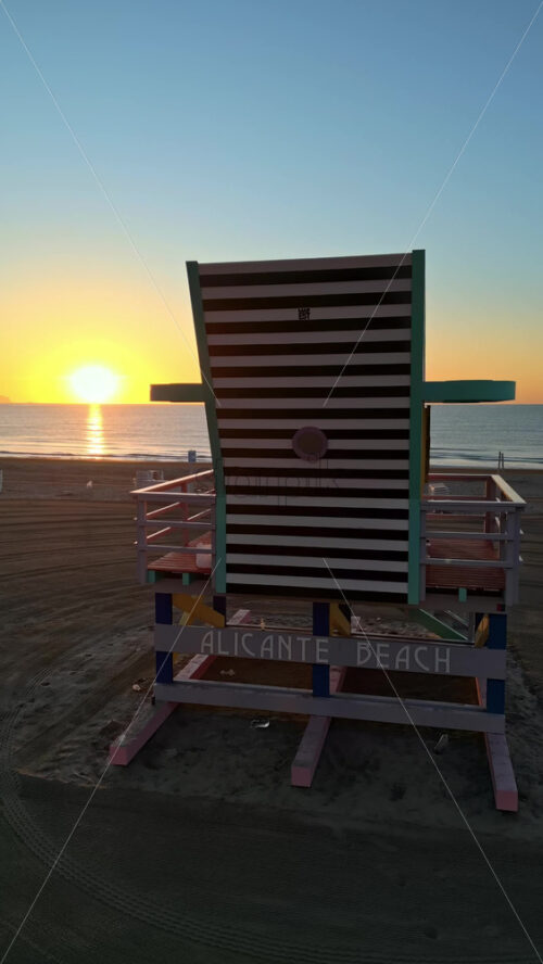 Aerial drone view of a colourful lifeguard tower on the San Juan Beach in Alicante, Spain at sunset. Vertical - Starpik Stock