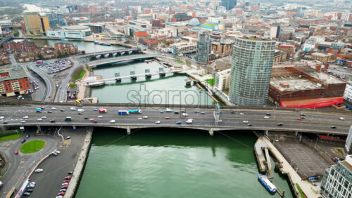 Aerial drone view of cars driving over the buildings surrounding River Lagan in Belfast, Northern Ireland - Starpik Stock