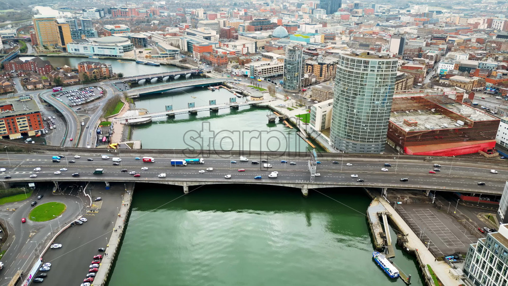 Aerial drone view of cars driving over the buildings surrounding River Lagan in Belfast, Northern Ireland - Starpik Stock