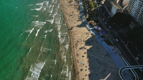 Aerial drone view of cars moving along the coastline with people relaxing on the beach in Alicante, Spain in daylight - Starpik Stock