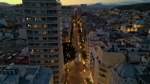 Aerial drone view of cars moving between the buildings in Alicante, Spain at sunset - Starpik Stock