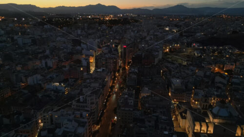 Aerial drone view of cars moving between the buildings in Alicante, Spain in the evening - Starpik Stock