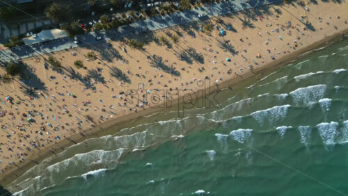 Aerial drone view of people relaxing on the beach in Alicante, Spain in daylight - Starpik Stock