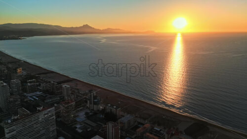 Aerial drone view of the Mediterranean Sea and the city of Alicante, Spain at sunset - Starpik Stock