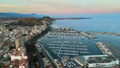 Aerial drone view of the Port of Alicante and the buildings in the city in the evening - Starpik Stock