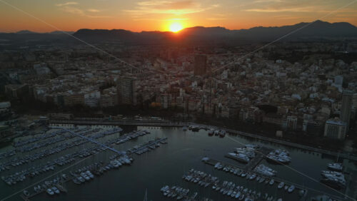 Aerial drone view of the Port of Alicante and the buildings in the city in the evening - Starpik Stock