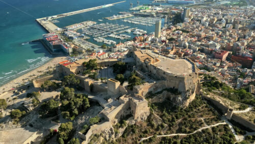 Aerial drone view of the Santa Barbara Castle on the coast of Alicante, Spain with the city and the sea on the background - Starpik Stock