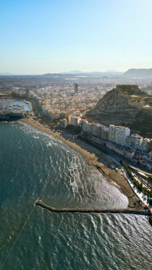 Aerial drone view of the Santa Barbara Castle on the coast of Alicante, Spain with the city and the sea on the background. Vertical - Starpik Stock