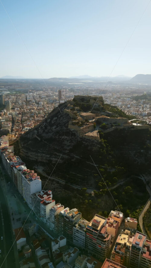 Aerial drone view of the Santa Barbara Castle on the coast of Alicante, Spain with the city and the sea on the background. Vertical - Starpik Stock