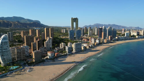 Aerial drone view of the buildings along the coastline and the sea in Benidorm, Spain in daylight - Starpik Stock