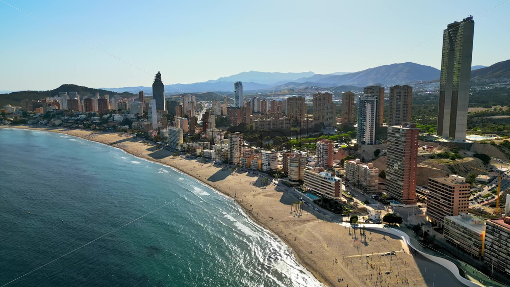 Aerial drone view of the buildings along the coastline and the sea in Benidorm, Spain in daylight - Starpik Stock