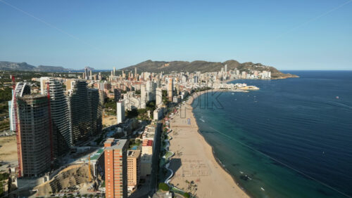 Aerial drone view of the buildings along the coastline and the sea in Benidorm, Spain in daylight - Starpik Stock