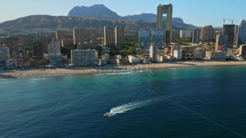 Aerial drone view of the buildings along the coastline with people parasailing in the sea in Benidorm, Spain in daylight - Starpik Stock