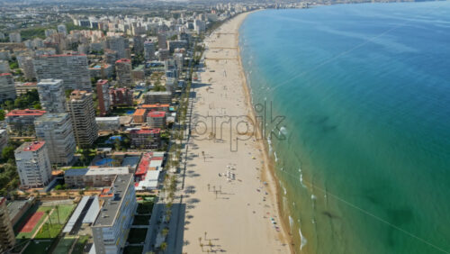 Aerial drone view of the buildings along the coastline with people relaxing on the beach in Benidorm, Spain in daylight - Starpik Stock