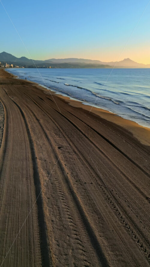 Aerial drone view of waves hitting the shore on the beach in Alicante, Spain. Vertical - Starpik Stock