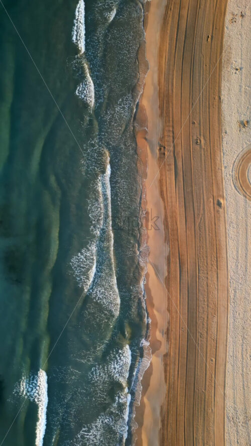 Aerial drone view of waves hitting the shore on the beach in Alicante, Spain. Vertical - Starpik Stock