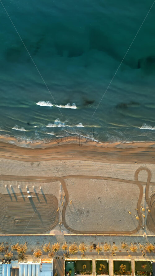 Aerial drone view of waves hitting the shore on the beach in Alicante, Spain. Vertical - Starpik Stock