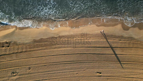 Man walking on the beach with waves hitting the shore in Alicante, Spain - Starpik Stock