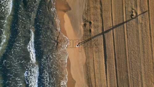Man walking on the beach with waves hitting the shore in Alicante, Spain - Starpik Stock