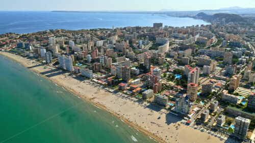 Video – Aerial drone view of the buildings along the coastline with people relaxing on the beach in Alicante, Spain in daylight - Starpik Stock