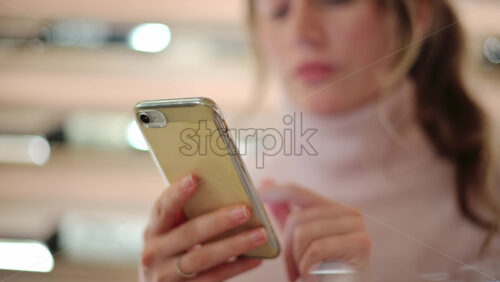 Video - Brunette woman scrolling on her phone at a restaurant