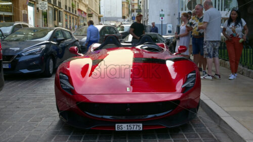Video - Monte Carlo, Monaco - October 4, 2024 : Red Ferrari parked on the street with people walking around