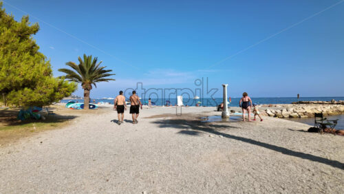 Video - Beaulieu-sur-Mer, France - July 5, 2024: People walking on the beach and relaxing in the sea at the Petite Afrique Beach