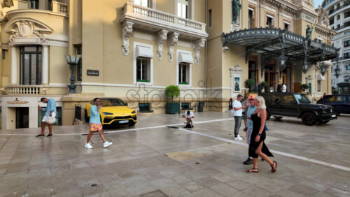 Video - Monte Carlo, Monaco - October 4, 2024: Luxury cars parked in the courtyard of the Monte Carlo Casino with people walking around