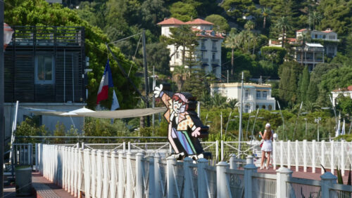 Video - Beaulieu-sur-Mer, France - July 5, 2024: Distant view of the Dancing Boy by Romero Britto figurine near a port