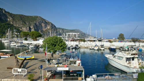Video - Beaulieu-sur-Mer, France - July 5, 2024: Boats docked in the port with the mountains on the background