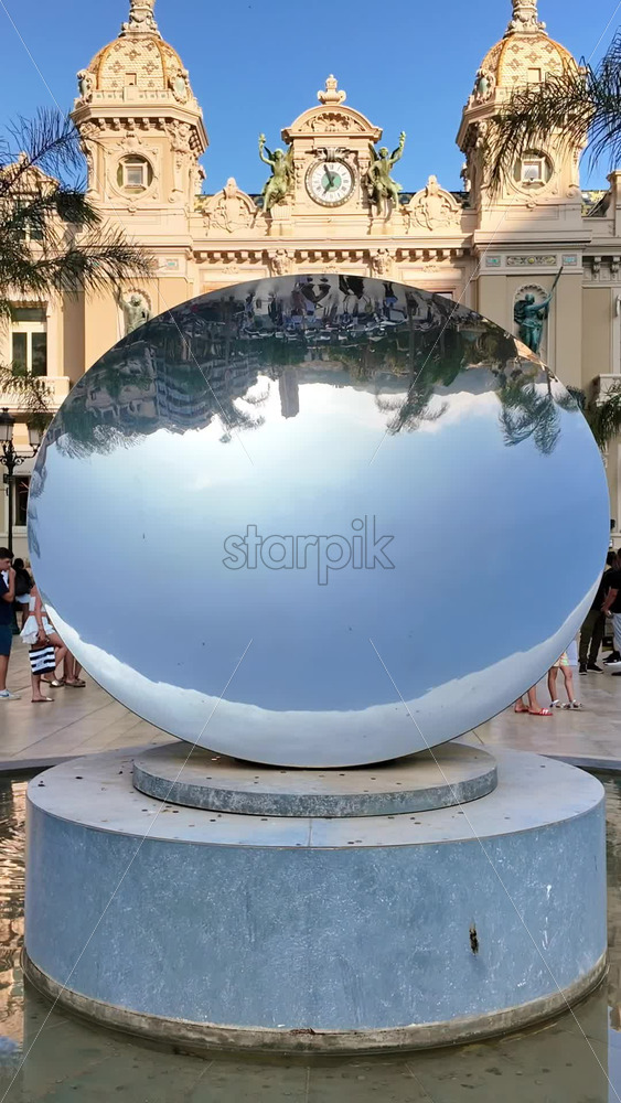 Video - Monte Carlo, Monaco - October 4, 2024: Sky mirror sculpture in front of The Monte Carlo Casino with people walking around it. Vertical