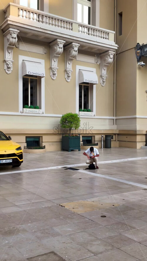 Video - Monte Carlo, Monaco - October 4, 2024: Luxury cars parked in the courtyard of the Monte Carlo Casino with people walking around. Vertical
