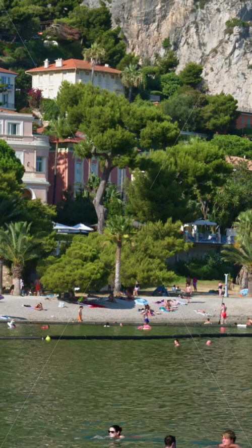 Video - Beaulieu-sur-Mer, France - July 5, 2024: People swimming and relaxing at the Petite Afrique Beach. Vertical