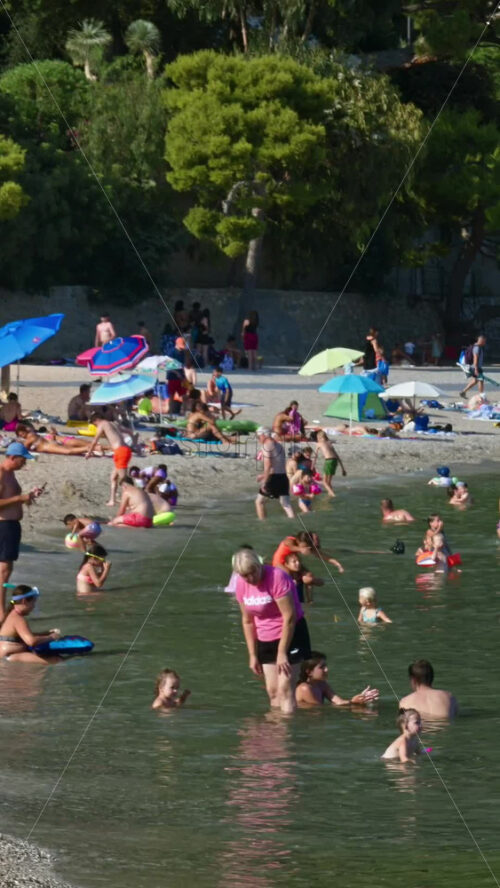 Video - Beaulieu-sur-Mer, France - July 5, 2024: People swimming and relaxing at the Petite Afrique Beach. Vertical