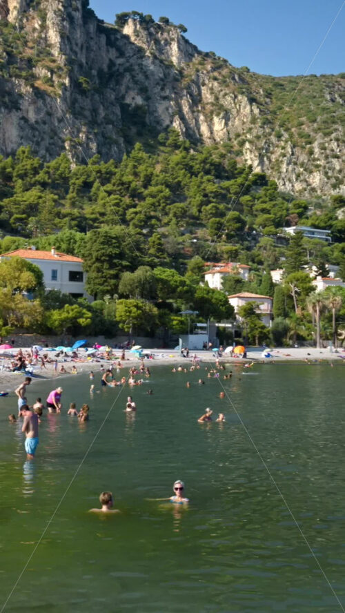 Video - Beaulieu-sur-Mer, France - July 5, 2024: People swimming and relaxing at the Petite Afrique Beach. Vertical